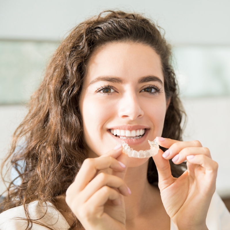 woman holding clear removable orthodontic aligners