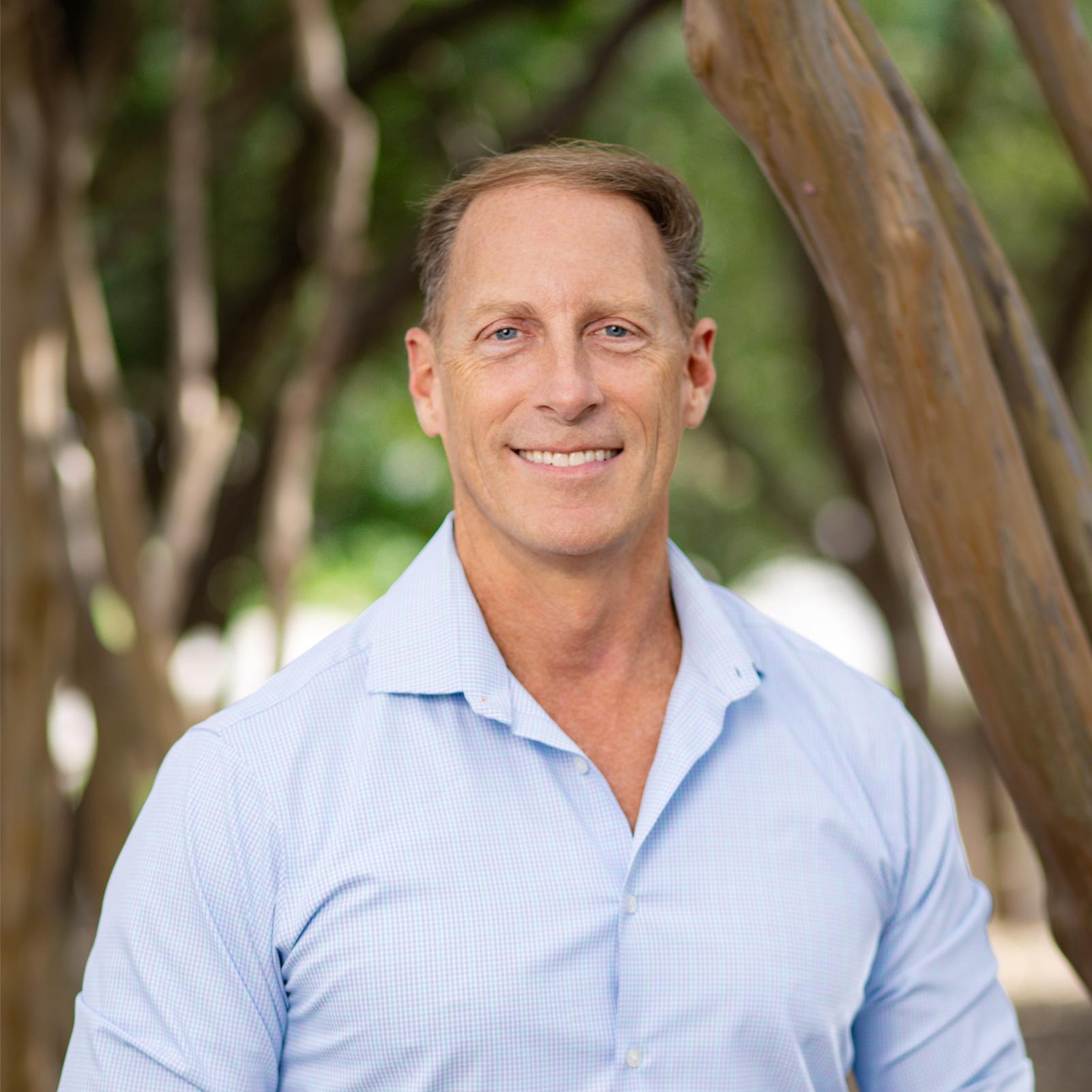 Dr. Jensen, Frisco orthodontist, smiling outdoors, showcasing personalized orthodontic care and expertise in clear aligners and braces.