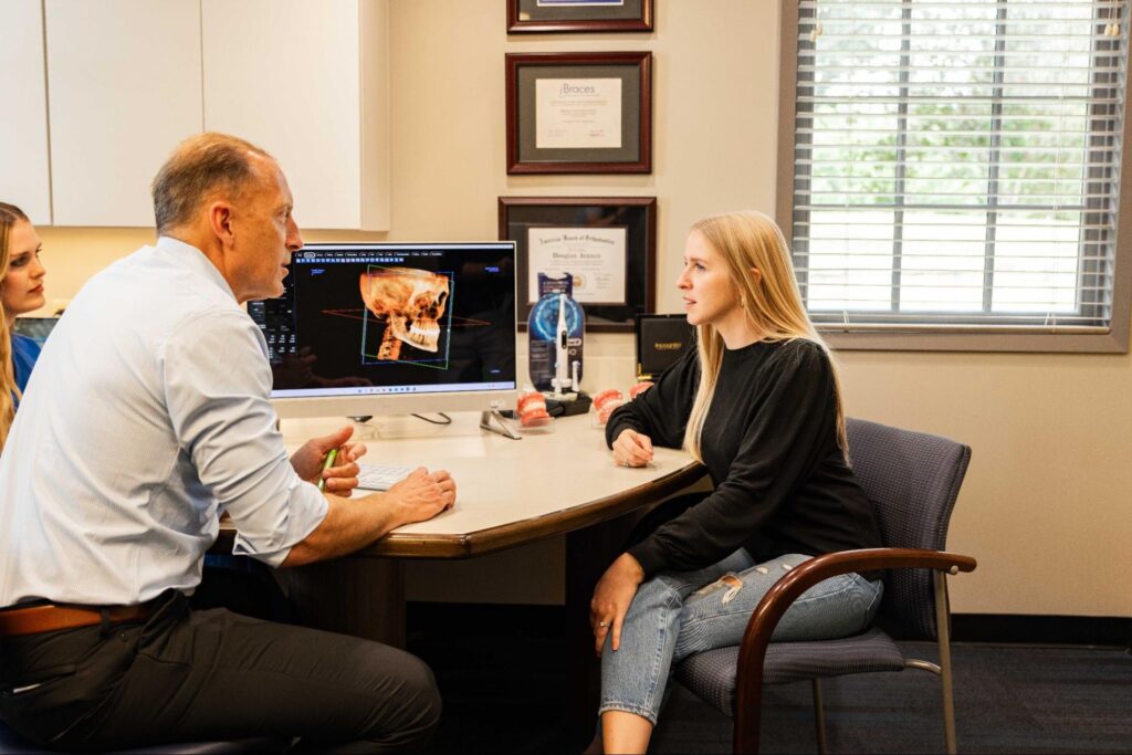 Doctor consulting with a patient, discussing orthodontic treatment options using digital imaging, in a professional office setting at Jensen Orthodontic Arts.
